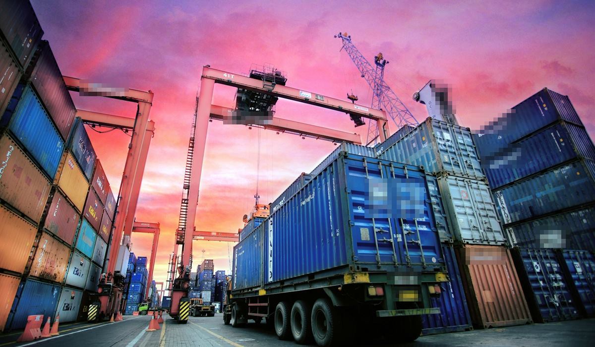 Caminhão transportando contêiner em um terminal portuário ao entardecer